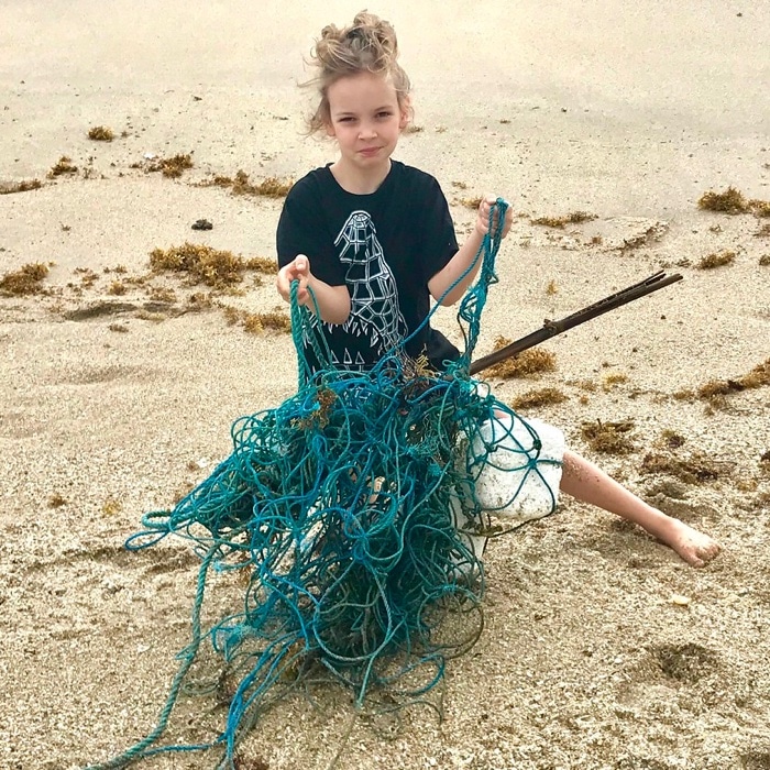Ella with discarded fish net on the beach